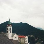Charming Italian village with a church tower against mountain backdrop in Lombardia, Italy.