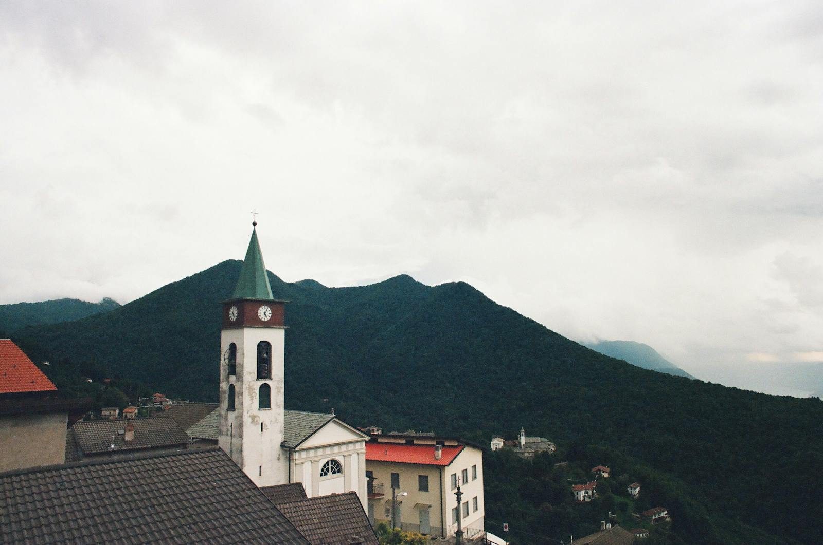 Charming Italian village with a church tower against mountain backdrop in Lombardia, Italy.