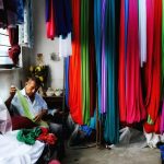 A tailor working with diverse textiles in a vibrant fabric shop, surrounded by colorful materials.