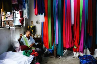 A tailor working with diverse textiles in a vibrant fabric shop, surrounded by colorful materials.