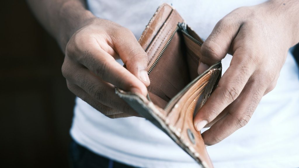 Person holding an empty brown leather bifold wallet.