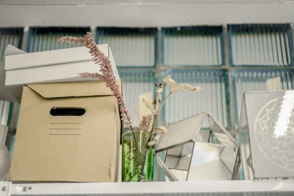 Cardboard box on white wooden shelf.