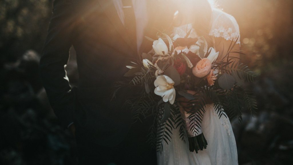 A groom beside a bride holding a bouquet of flowers.