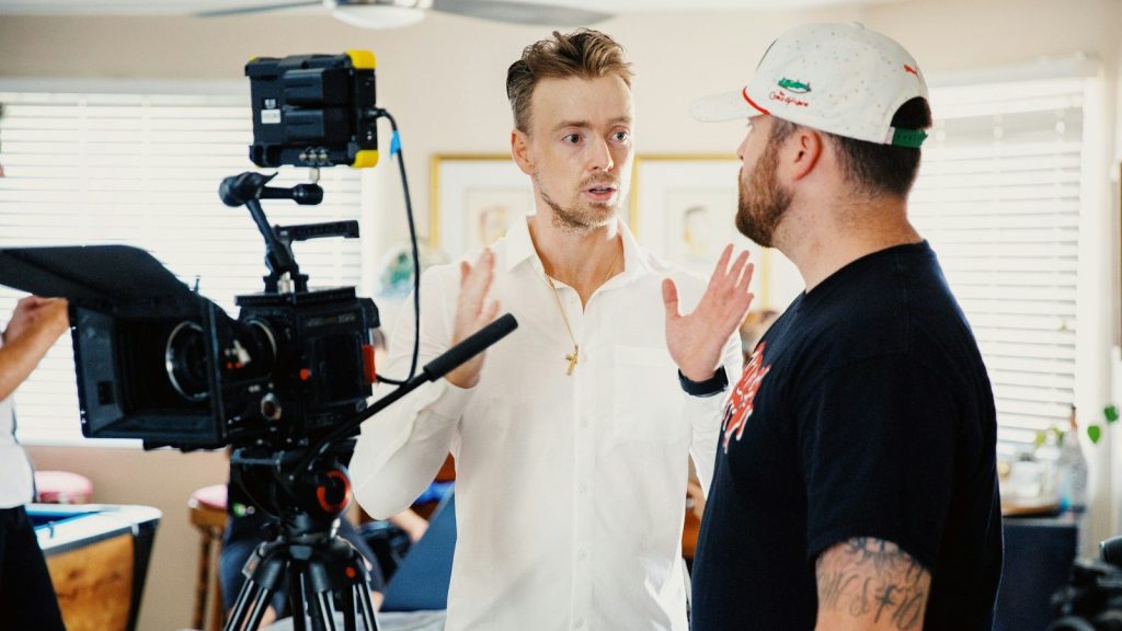 Film crew members engage in an intense discussion beside professional camera equipment.