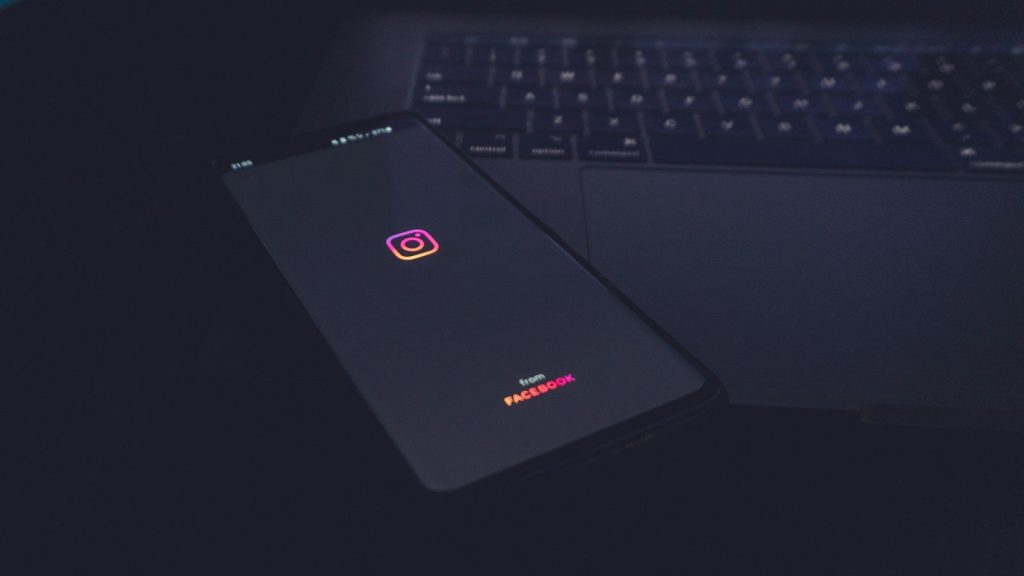 The Instagram logo on the smartphone kept on the laptop.
