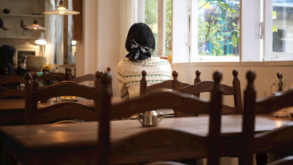 A woman sitting at a table by the window in a restaurant.