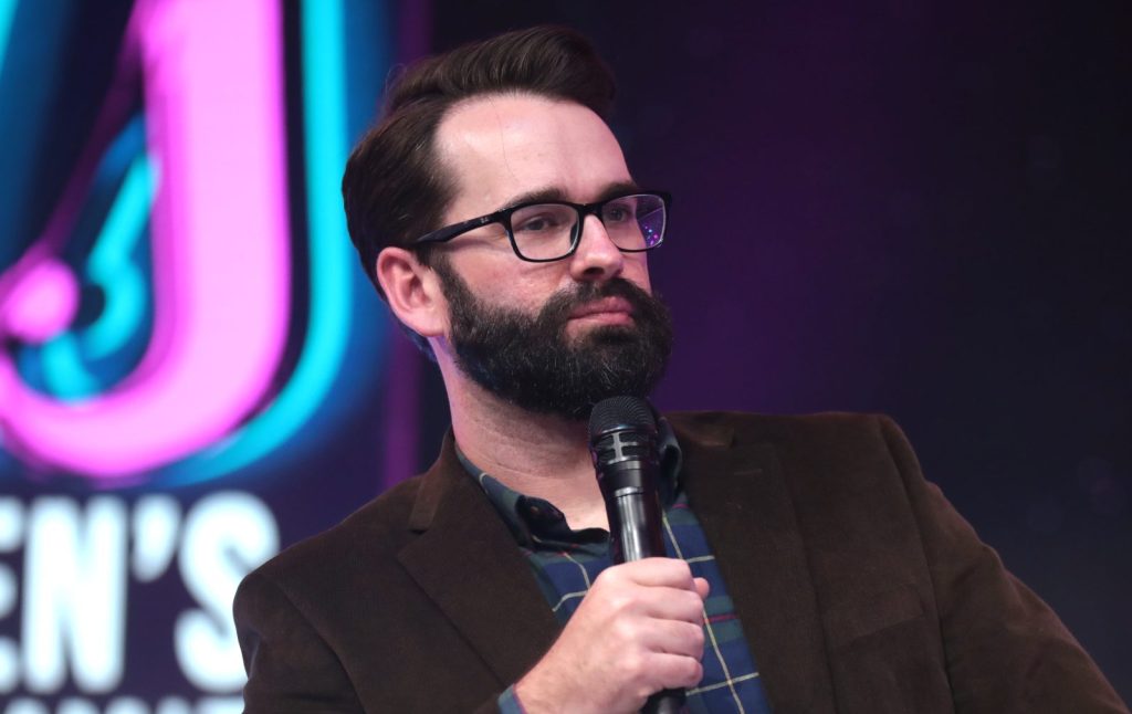 Matt Walsh at a live event holding a microphone.