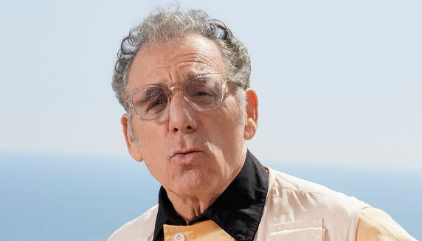 Michael Richards standing outdoors against a bright coastal background.