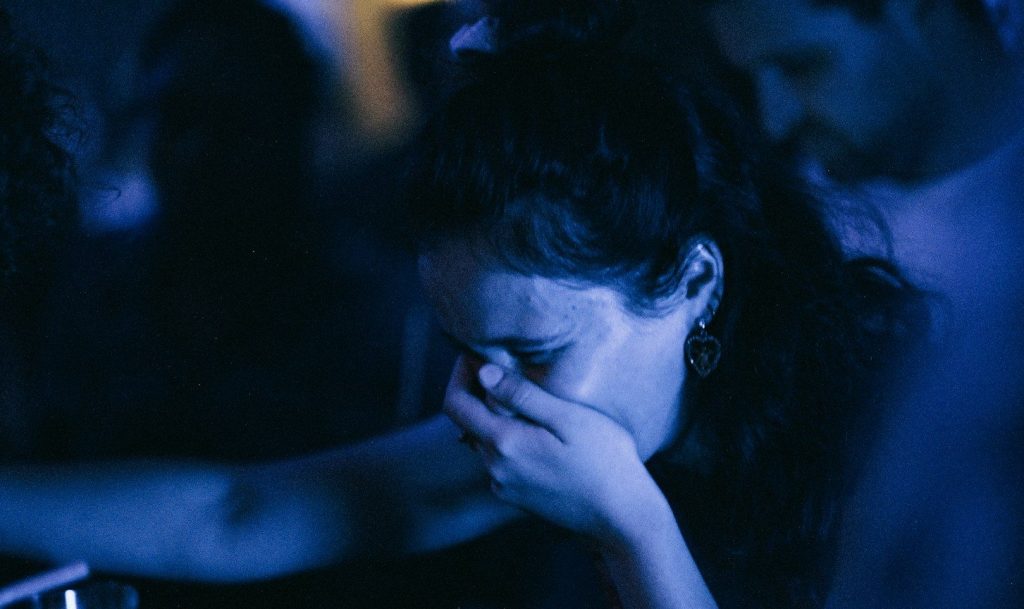 A woman crying while covering her mouth.