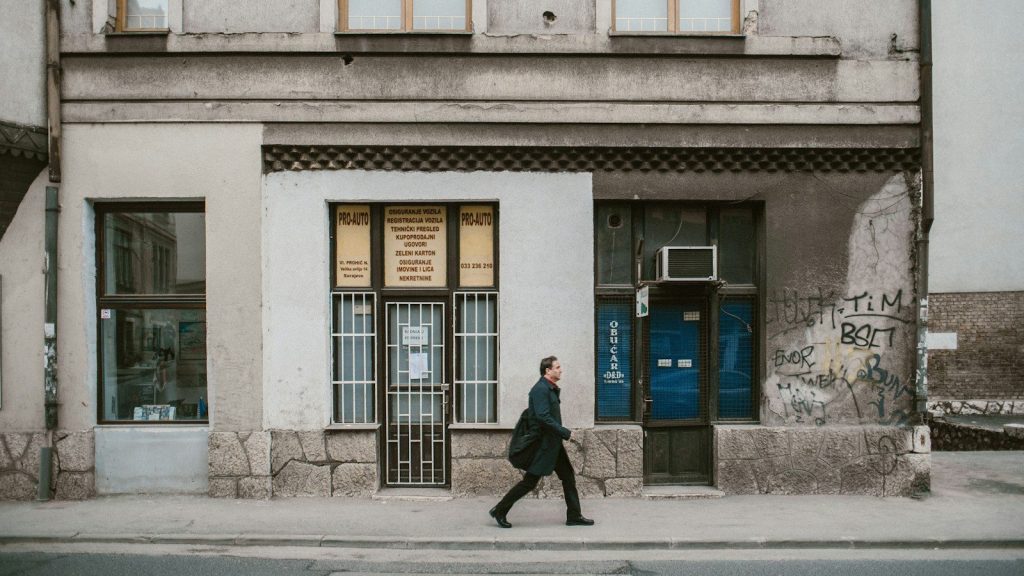 A man wearing a black coat walking on the street.