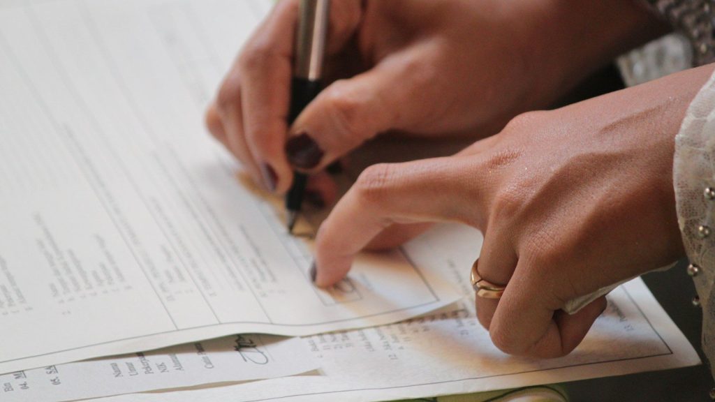 Close-up of a woman's hand signing papers.