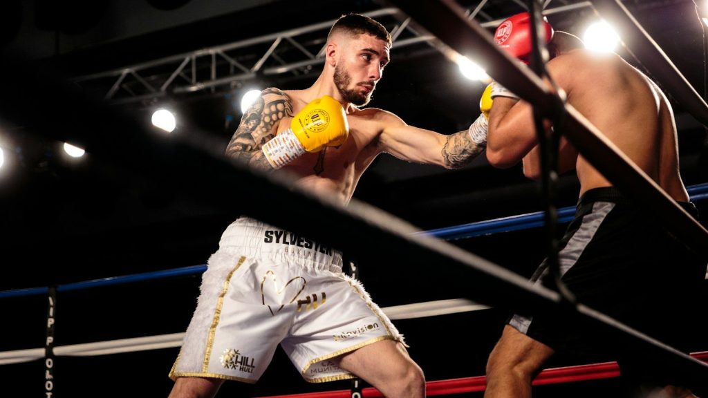 A boxer hitting another boxer inside a boxing ring.