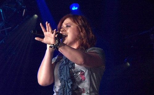 Kelly Clarkson singing during a live concert.