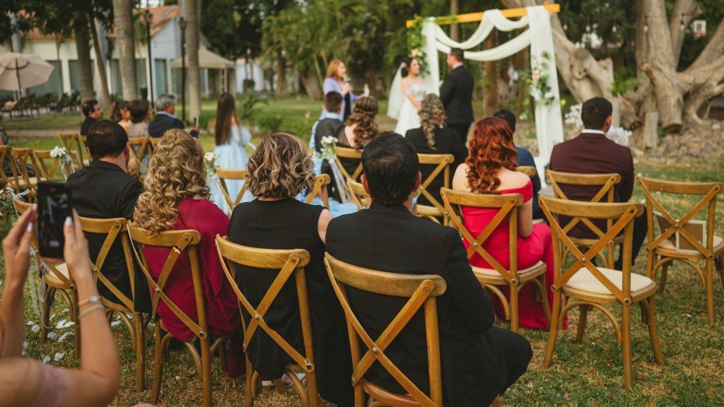 Wedding ceremony with guests seated outdoors.