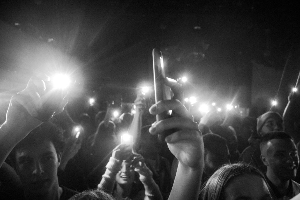A crowd of people holding up their cell phones, flashing their lights.