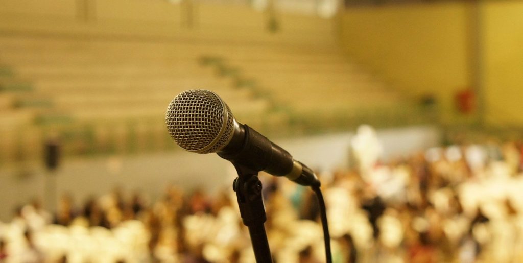 Black corded microphone with a room full of people in the blurred background.