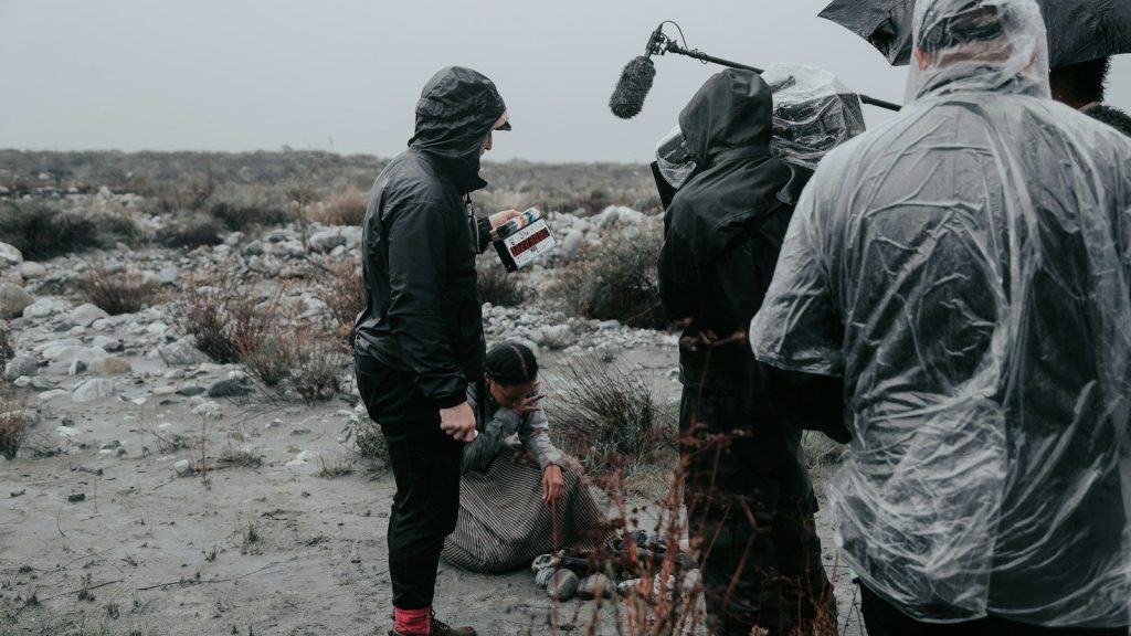 A film directing team standing beside a person holding a microphone during the day.