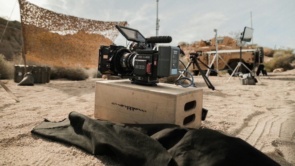 Black DSLR camera on a brown cardboard box in a desert setting.