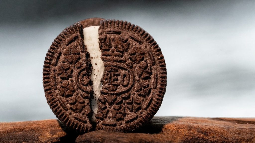 Close-up of Oreo split open to reveal white cream filling on a wooden surface.