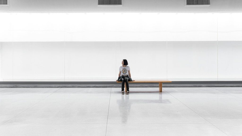 A woman sitting on a bench alone in a large room.