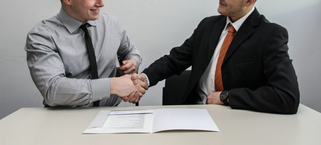Two men facing each other while shaking hands.