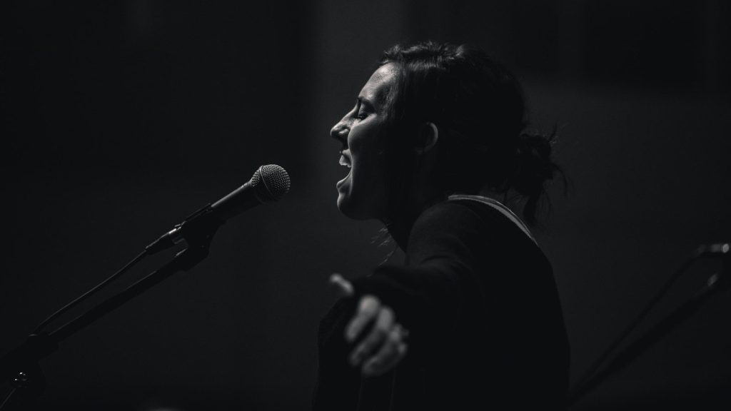A woman standing beside a microphone singing.