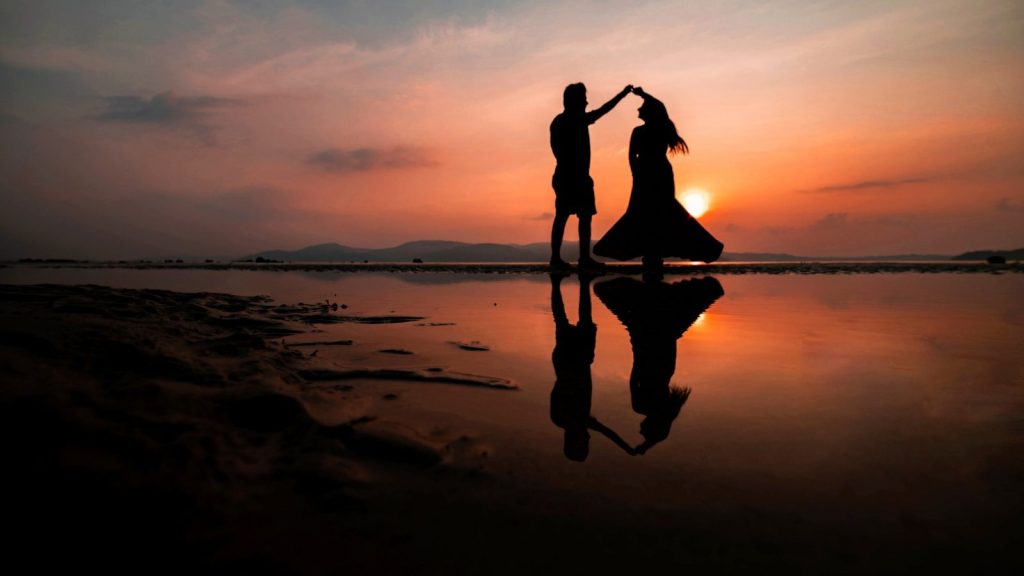 A silhouette of a couple at the beach during sunset.