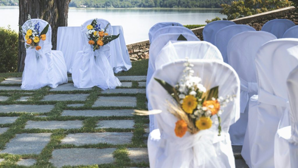 White clothed chairs with yellow and orange flowers on back.