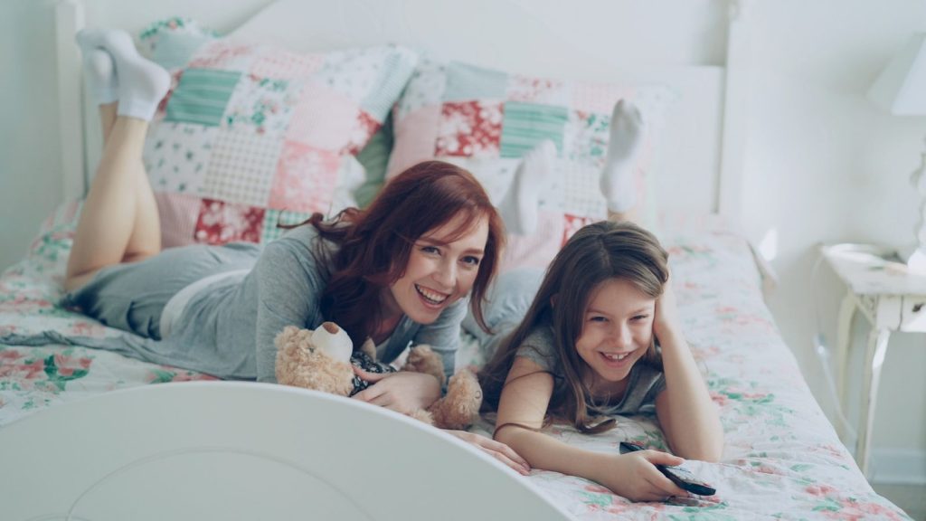 Two girls smiling by watching TV.