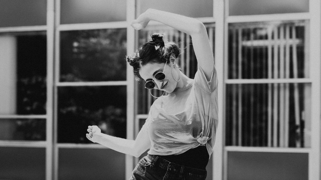 A woman dancing while wearing sunglasses.