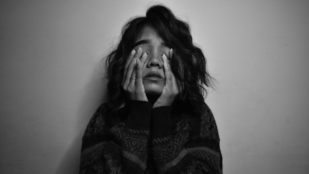 A woman covering her face with her hand.