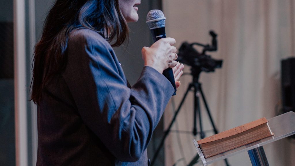 A woman standing while holding a microphone.