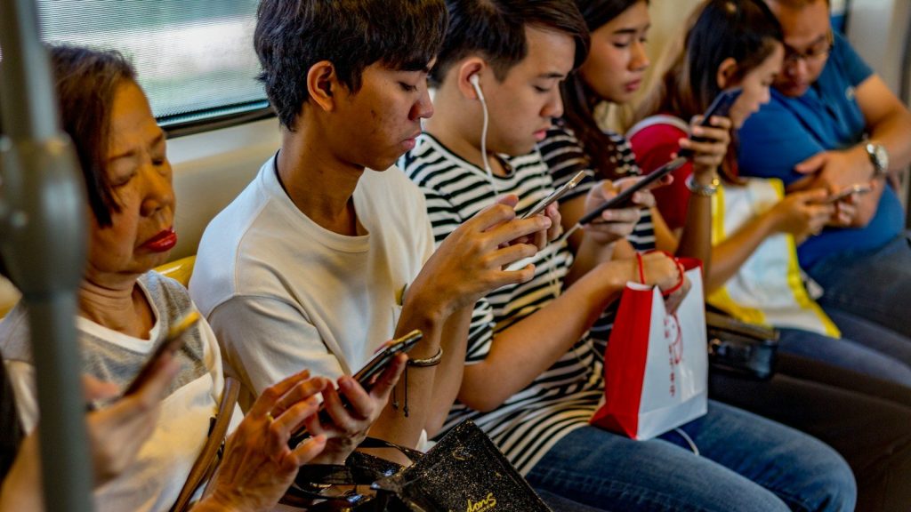 People using smartphones while sitting inside a train.