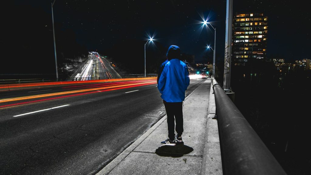 A person standing on the street at night.