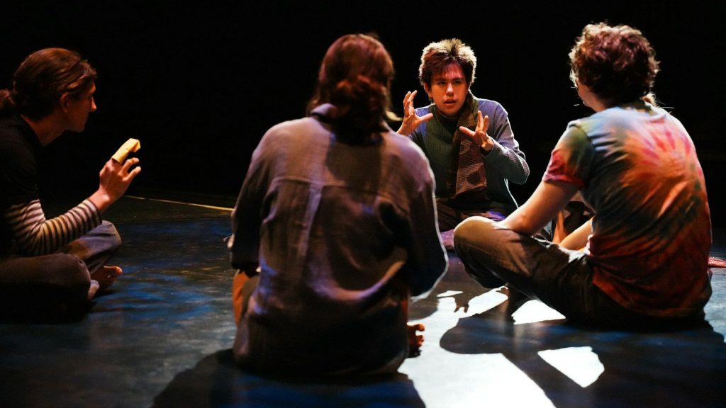 A group of people sitting on the floor talking.
