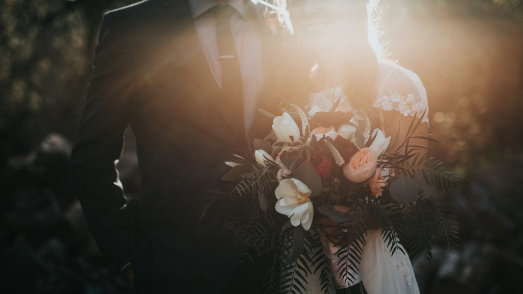 Groom beside bride holding bouquet flowers.