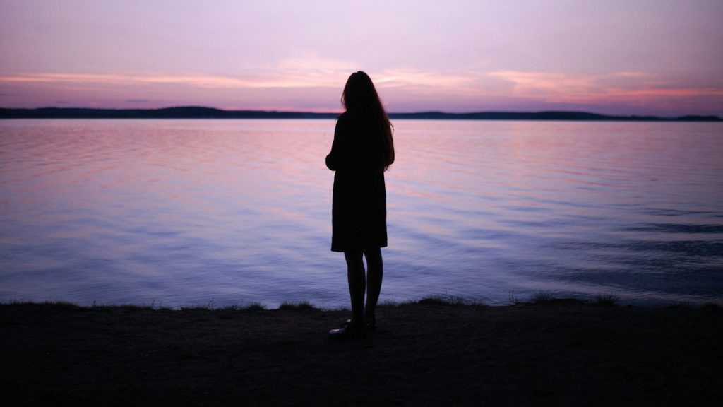 Silhouette of a woman standing near water.