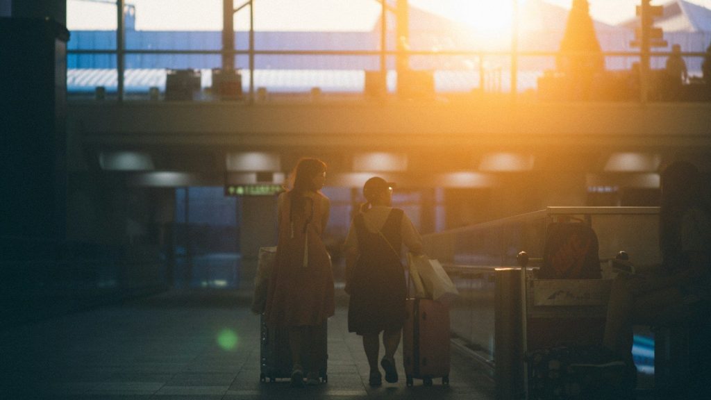 Two women walking with luggage bags.