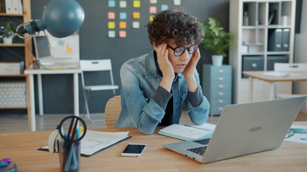 A person looking stressed at a laptop.