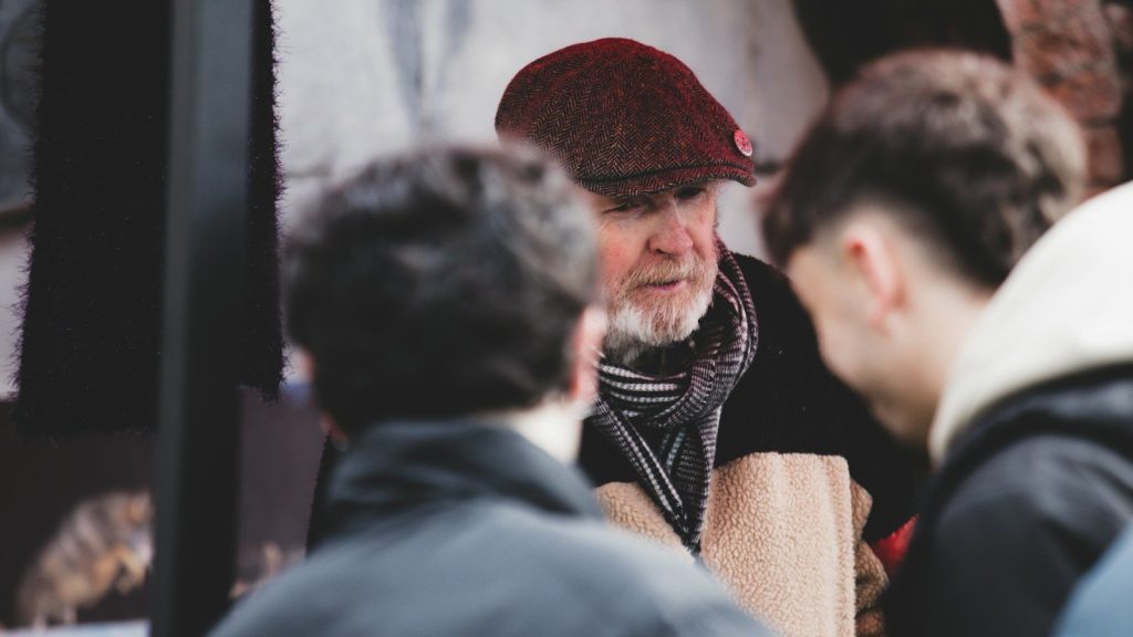 A man in cap talking to two younger men.