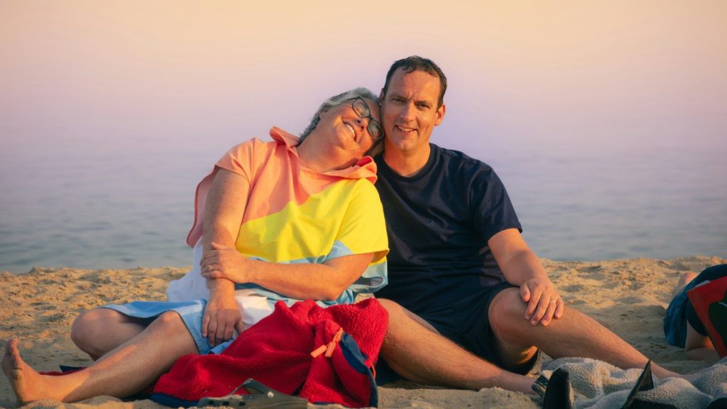 A man and a woman sitting on a beach.