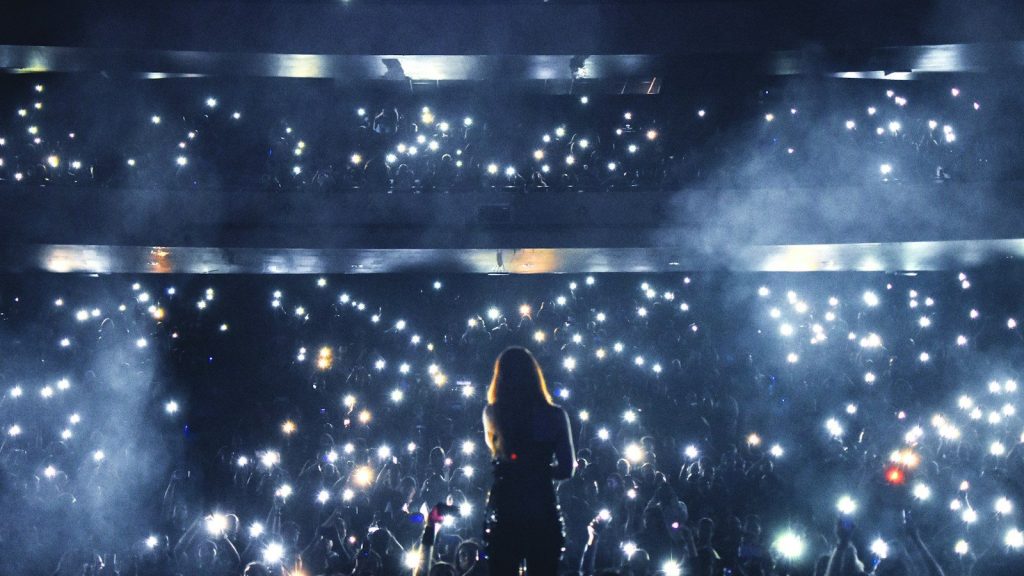 A silhouette of a woman standing on stage with lights.