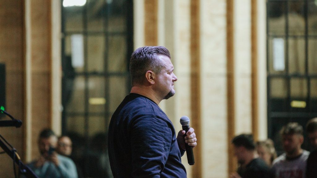 A man holding a microphone in front of a group of people.