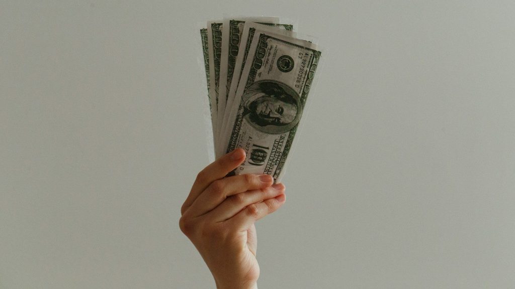 A person holding 100 US dollars.