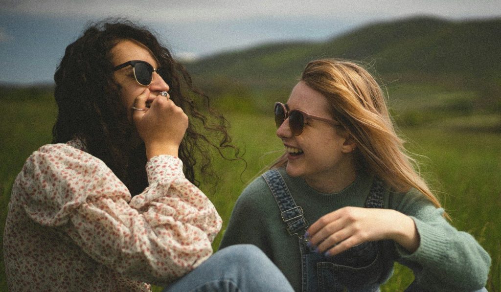 Women sitting on the grass field during the daytime.