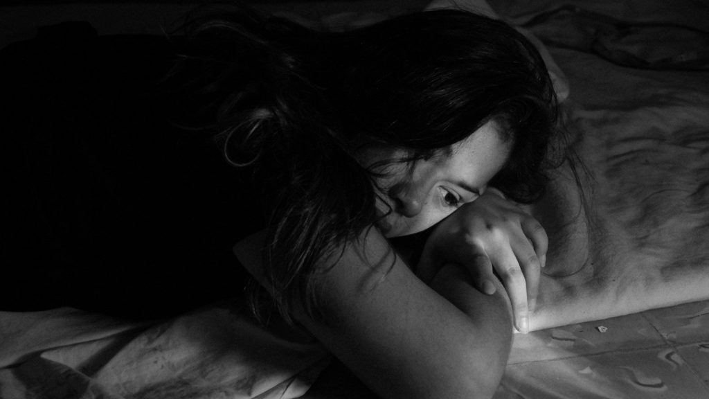 woman lying on a bed looking sad