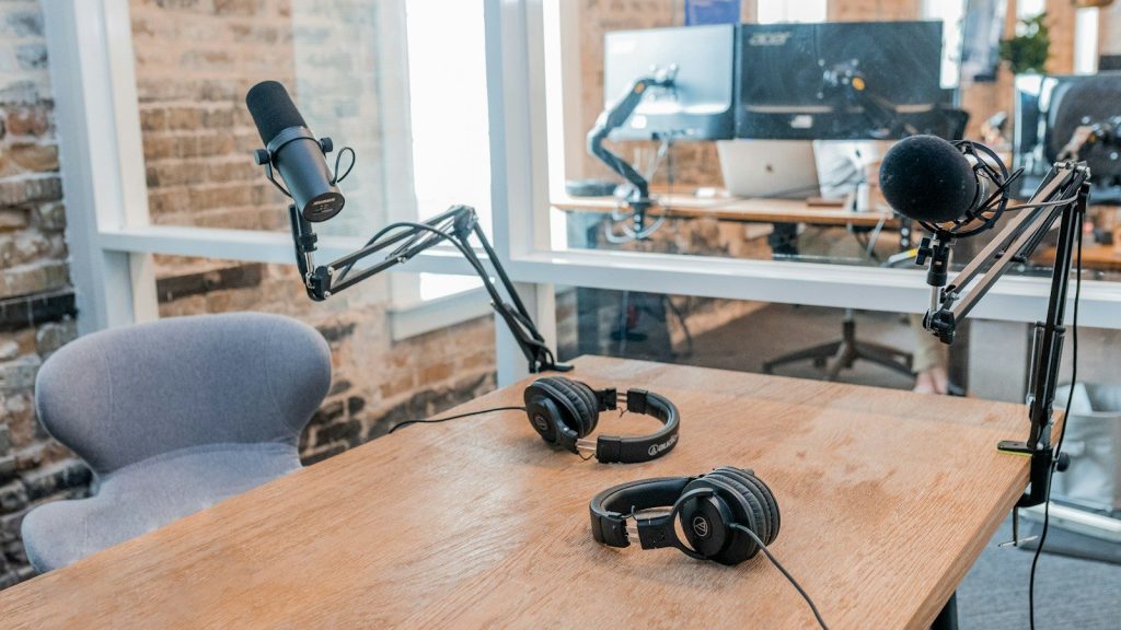 Two black headphones on brown wooden table.