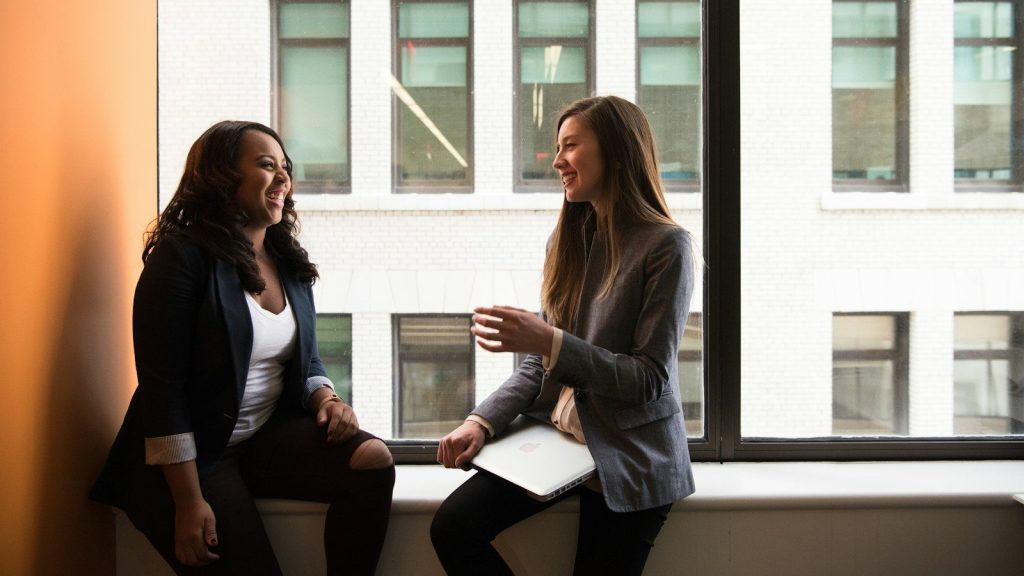 Two woman sitting by the window talking.