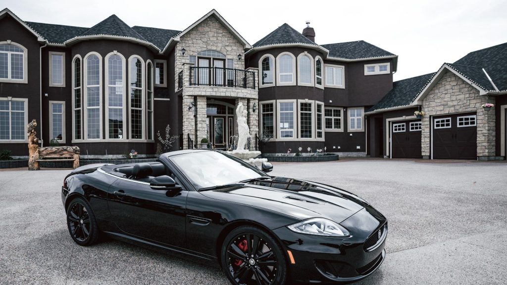 A car parked near a big luxury house.