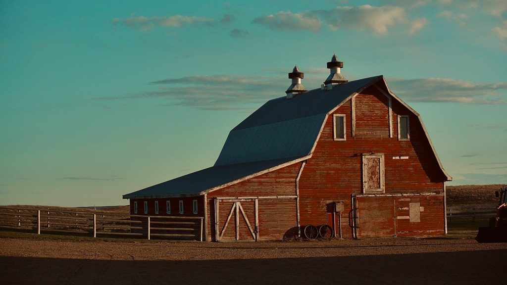 Red wooden barn under blue sky during daytime.